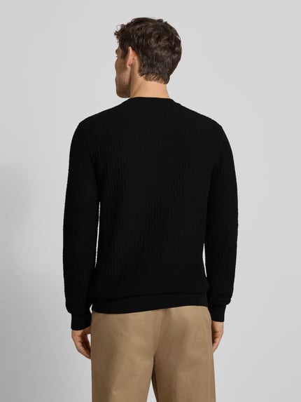 Männermodel trägt Regular Fit Strickpullover aus reiner Baumwolle Modell 'IMBERTO' von BOSS, schwarz, Strukturmuster, Ganzkörperansicht Rückansicht.