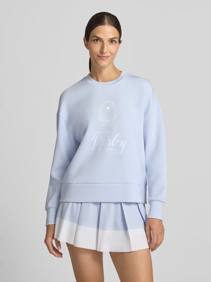 Frauenmodel trägt Sweatshirt aus Viskose-Mix Modell 'rasco' von VARLEY in Hellblau mit geripptem Rundhalsausschnitt, elastischen Abschlüssen, Label-Stickerei und lockerer Passform, Ganzkörperansicht von vorne.