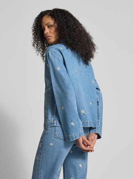 Frauenmodel trägt Jeansjacke mit Stitchings und Schnürung von Jake*s Casual in Hellblau mit Blümchenmuster, Relaxed Fit, Ganzkörperansicht Rückansicht.