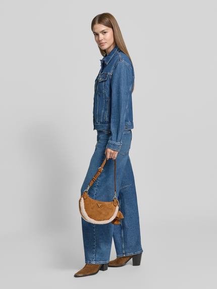 Vrouwenmodel draagt Handtasche mit Teddyfell Modell 'KATIE' van GUESS in leerlook met teddybont, hoofvak met ritssluiting, labelapplicatie, cognackleur, rechthoekige vorm, zachte textuur. Ganzkörperansicht van voren.