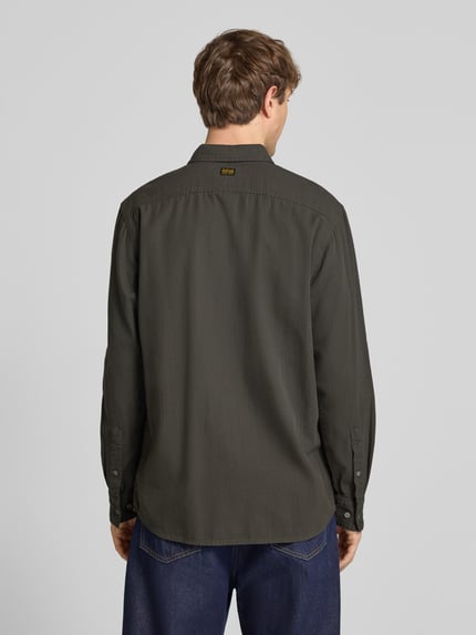 Männermodel trägt Regular Fit vrijetijdsoverhemd uit puur katoen van G-Star Raw in olijfkleur, ruglengte maat M 74 cm, schouderbreedte 45 cm, mouwlengte 67 cm, kentkraag, knoopsluiting, heren vrijetijdsoverhemd, geheelachteraanzicht.