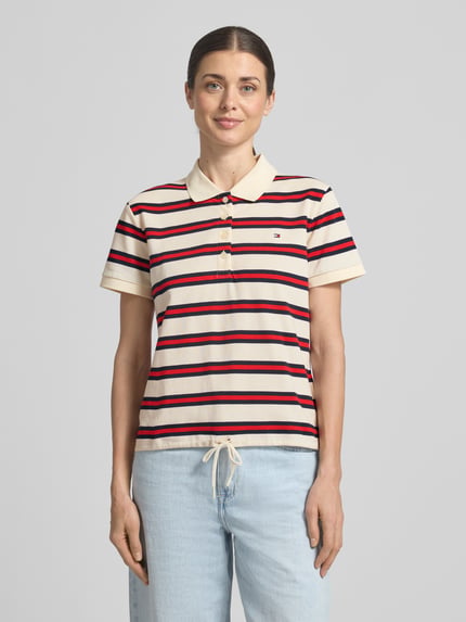 Frauenmodel trägt Regular Fit Poloshirt aus Baumwoll-Mix von Tommy Hilfiger, gestreift, mit Logo-Detail, Polokragen, Ganzkörperansicht von vorne.