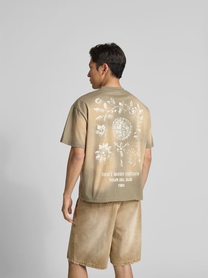Męski model nosi t-shirt z nadrukiem z logo od Don’t Waste Culture z czystej bawełny, prosty krój, okrągły dekolt, nadruk z logo, rękawy obniżone, długość tyłu w rozmiarze M: 65 cm, widok całej sylwetki z tyłu.