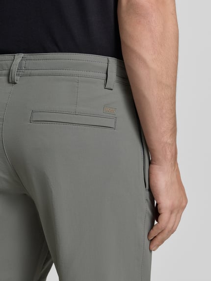 Männermodel trägt Straight-Tapered Fit Chino mit Bund Tunnelzug Modell 'CHINO' von BOSS Orange in Grau, Detailaufnahme Rückansicht.