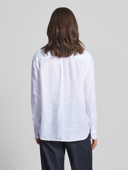 Vrouwenmodel draagt overhemdblouse uit zuiver linnen met kentkraag model 'MIRA' van 0039 Italy, regular fit; wit, fijne textuur, sportmanchet. Ganzkörperansicht Rückansicht. Ruglengte maat S: 68 cm, mouwlengte maat S: 62 cm, knoopsluiting.