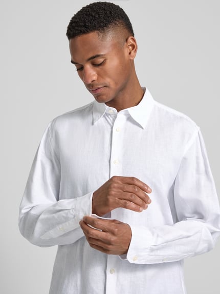 Männermodel trägt Regular Fit Freizeithemd aus Leinen-Baumwoll-Mix Modell 'CLAY LINENBLEND' von SELECTED HOMME, Melange-Optik, Weiß, durchgehende Knopfleiste, Kentkragen, 2-Knopf-Manschette, Flammgarn, Nahaufnahme Oberkörper.
