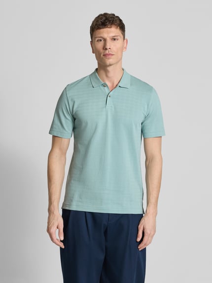 Męski model nosi Regular Fit Poloshirt aus reiner Baumwolle von Marc O'Polo, jednolity kolor, kratka, wyhaftowane logo, kołnierzyk polo, dekolt w serek, zapięcie na 2 guziki, krótki rękaw, prążkowane zakończenia, z bocznymi rozcięciami, żakard, bawełna, widok całej sylwetki z przodu.