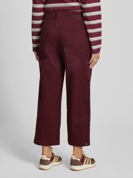 Männermodel trägt spodnie sztruksowe 'Loose Fit Cordhose aus reiner Baumwolle' von Marc O'Polo DENIM, bordowy, szerokie nogawki, tekstura sztruksu, Ganzkörperansicht Rückansicht