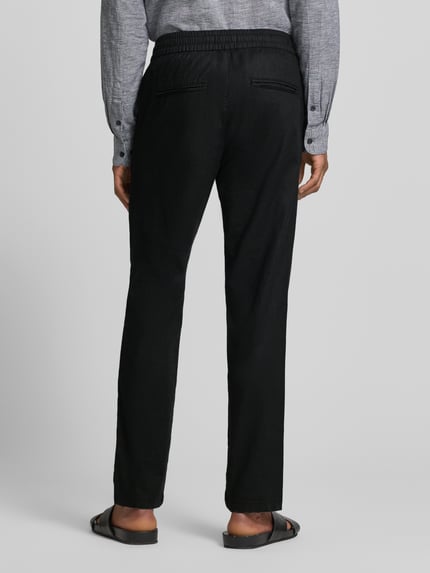 Männermodel trägt schwarze Straight Fit Leinenhose mit elastischem Bund Modell 'Barton' von Matinique, Leinen-Baumwoll-Mix, Ganzkörperansicht Rückansicht.
