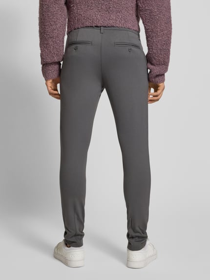 Männermodel trägt Slim Fit Chino aus Viskose-Mix Modell 'MARK' von Only & Sons in Unifarben mit Gesäßtaschen, Ganzkörperansicht Rückansicht.
