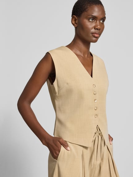 Vrouwenmodel draagt Slim Fit bodywarmer met viscose, model 'DYLAN' van SUNCOO PARIS in beige, materiaalmix, V-hals, knoopsluiting, ganzendbovenaanzicht.