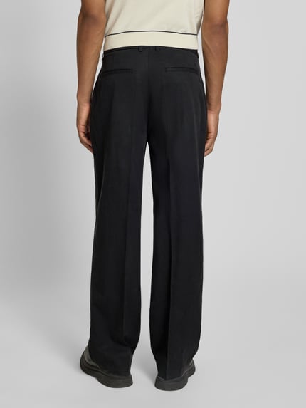 Männermodel trägt schwarze Hose mit Bügelfalten Modell 'Reece' von Les Deux, Regular Fit, Lyocell-Baumwoll-Mix, Ganzkörperansicht Rückansicht.