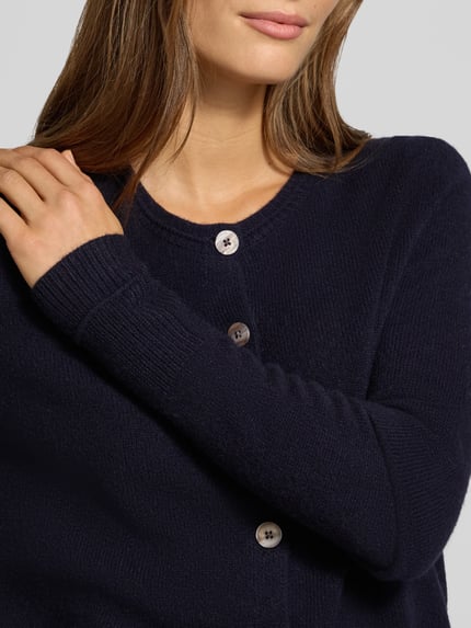 Frauenmodel trägt Cardigan aus Wolle mit Rundhalsausschnitt von Christian Berg Woman in Dunkelblau, Knopfleiste, Nahaufnahme Oberkörper.