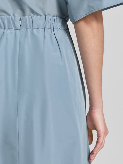 Kobieta nosi spódnicę midi z bawełnianym dodatkiem model 'FORMICA' od Weekend Max Mara, jednokolorowy, rozkloszowany krój, długość midi, kontrafałdy, wszyty zamek błyskawiczny, elastyczny pas, prosty dół, boczne wpuszczane kieszenie, zdjęcie detailaufnahme tylnej części.