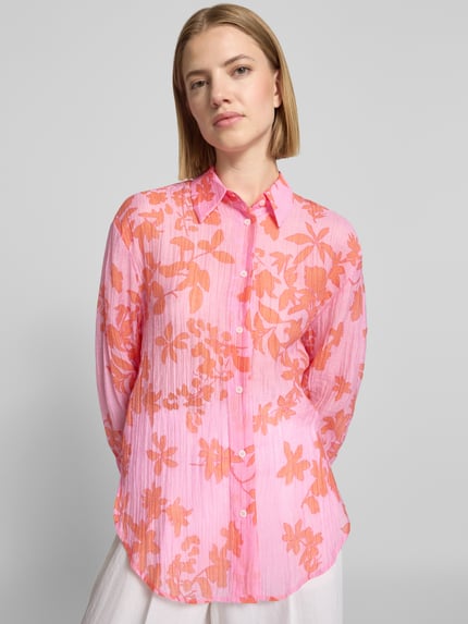 Frauenmodel trägt Regular Fit Hemdbluse aus Lyocell-Mix von Mango, Rosa mit orangen floralen Print, semitransparent, Ganzkörperansicht von vorne.