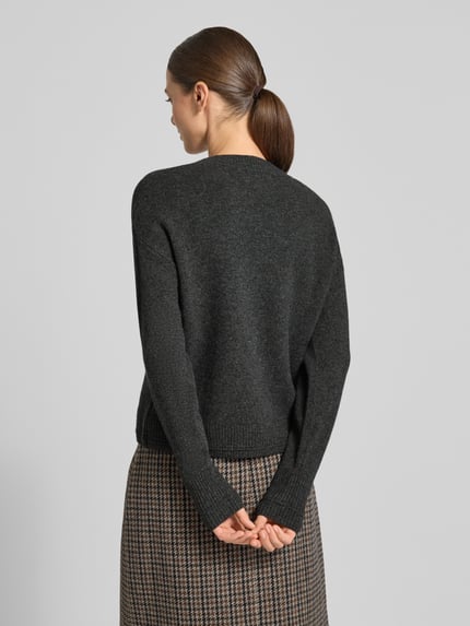 Modelka nosi Strickpullover mit überschnittenen Schultern od Christian Berg Woman w kolorze ciemnoszarym, faktura dzianinowa, długie rękawy, okrągły dekolt, luźny fason; widok sylwetki od tyłu.