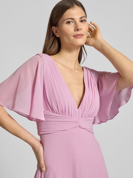 Kobiece modelka nosi Sukienka wieczorowa Regular Fit Abendkleid mit V-Ausschnitt von Jake*s Cocktail, szyfon, dekolt w serek, krój regular fit, rękaw o dł. 1/2, efekt plisowania, dekolt na plecach, wszyty zamek błyskawiczny, halka pod spódnicę, jasnoróżowa, gładka tekstura, z przodu, zbliżenie na górną część ciała