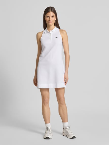 Vrouwenmodel draagt Slim Fit Polokleid aus Baumwoll-Mix van Lacoste, look: effen kleuren, minilengte, V-hals, logodetail, piqué katoenmix, ganzkörperaanzicht van voren.