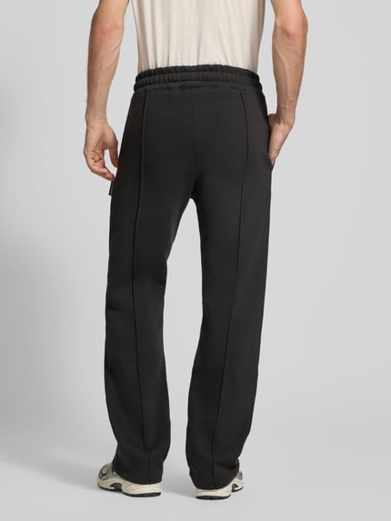 Männermodel trägt Sweatpants mit elastischem Bund und Label-Stitching von PROHIBITED im Loose Fit, schwarz, Ganzkörperansicht Rückansicht. Baumwoll-Mix, Innenbeinlänge 80 cm bei Größe M.