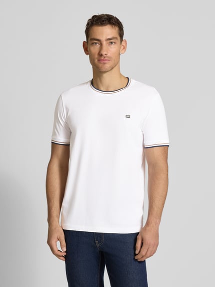 Männermodel trägt T-Shirt mit Kontraststreifen und Rundhalsausschnitt von Christian Berg Men aus Baumwoll-Elasthan-Mix, Regular-Fit, Rückenlänge 71 cm bei Größe M, weiß mit dunklen Akzenten, glatte Textur, Ganzkörperansicht von vorne.
