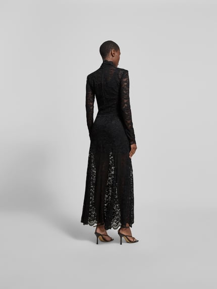 Männermodel trägt Maxikleid aus Spitze mit Stretch-Anteil von Rabanne, czarny kolor, koronkowa faktura, krój slim fit, całkowita długość 149 cm, szerokość w rozmiarze S/M: 40 cm, szerokość w talii w rozmiarze S/M: 31 cm, długość rękawa 68 cm, długi rękaw, stójka, widok całej sylwetki z tyłu