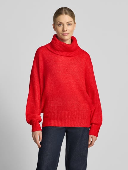 Frauenmodel trägt Relaxed Fit sweter z dzianiny z golfem Model 'IHKAMARA' od ICHI, Mieszanka materiałów z domieszką alpaki, elastyczne wykończenia, długość tyłu 63 cm w rozmiarze S, długość rękawów 72 cm w rozmiarze S, intensywnie czerwony kolor, gładka struktura, widoczne mankiety, Ganzkörperansicht von vorne.