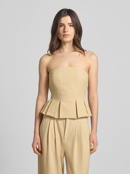 Vrouwenmodel draagt Slim Fit corsage met viscose, model 'Stacy' van Gestuz in beige met stolpplooien, strapless ontwerp, elastische materiaalmix, ruglengte bij maat 36 is 26 cm, volledige voorkantaanzicht