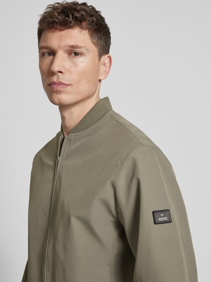 Männermodel trägt bomberjack met opstaande kraag model 'BLAASPEN' van Jack & Jones Premium, materiaalmix met stretch, los model, ritssluiting, zij-steekzakken, elastische boorden, kleur olijfgroen, Nahaufnahme Oberkörper.