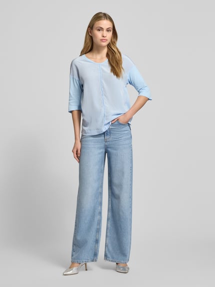 Kobiece model prezentuje T-shirt z dekoltem w serek i rękawem o dł. 3/4 od Marc Cain, mieszanka bawełny i elastanu, krój regular fit, długość tyłu 58 cm, cała sylwetka z przodu.