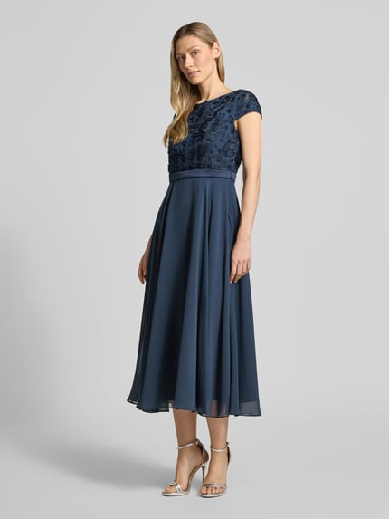Kobiece modelka nosi Cocktailkleid mit Stitchings und Perlen von Christian Berg Cocktail, mieszanka materiałów z dodatkiem streczu, linia a, sukienka midi, hafty, perły, okrągły dekolt, długość tyłu w rozmiarze 36: 124 cm, szerokość w rozmiarze 36: 45 cm, granatowy, gładka tekstura spódnicy, połyskliwe detale, widok całej sylwetki z przodu.