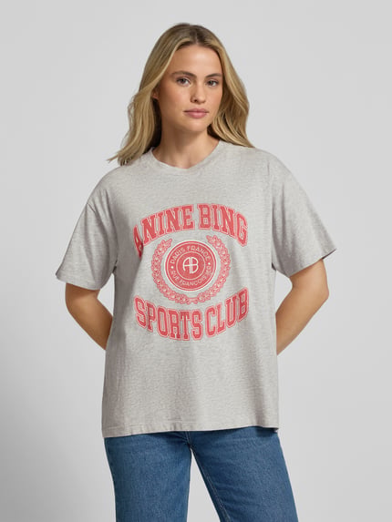 Vrouwenmodel draagt Relaxed Fit T-Shirt uit puur katoen van Anine Bing met ronde hals, labelprint, met korte mouwen, grijs en rood, vooraanzicht, ruglengte bij maat S: 63 cm.