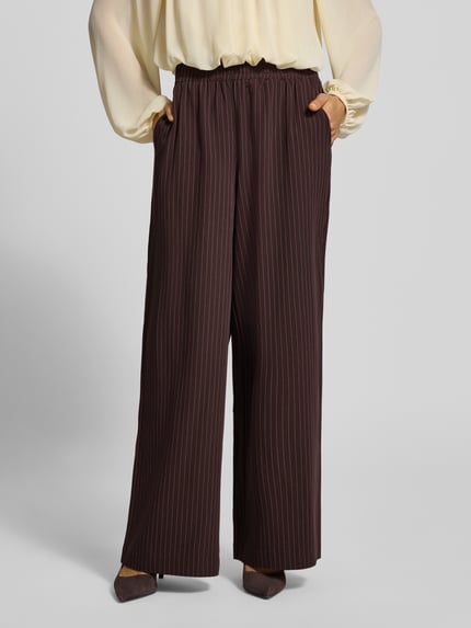 Vrouwenmodel draagt Regular Fit broek met elastische band van YAS, mat krijtstreeplook, elastiek aan boord, krijtstreepmotief, wijdte, Dames, stoffen broek, detail: elastiek, donkerbruin, detailopname onderlichaam.