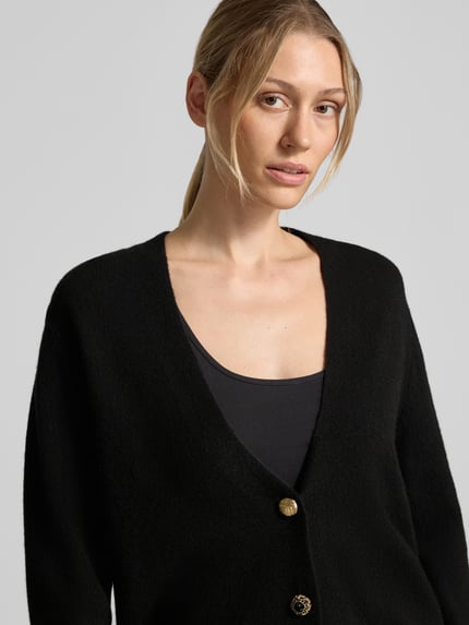 Frauenmodel trägt Relaxed Fit Cardigan aus reiner Wolle Modell 'Maglia Aperta' von Liu Jo White, Strick-Optik, Schwarz, Nahaufnahme Oberkörper.