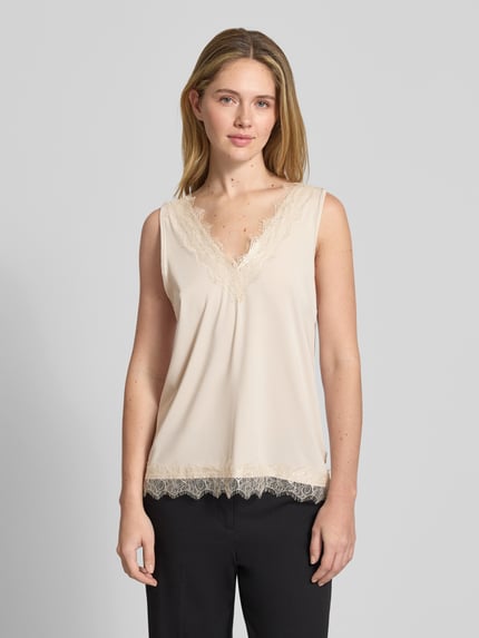 Frauenmodel trägt Trägertop aus Satin mit Spitzenbesatz Modell 'Bicco' von FREE/QUENT in Creme, Regular-Fit, V-Ausschnitt, Nahaufnahme Oberkörper. Damen Trägertop, Rückenlänge bei Größe S 43 cm, glatte Satinstruktur mit zarten Spitzen-Details.