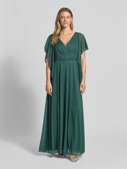 Frauenmodel trägt Maxikleid in Glitzer-Optik mit V-Ausschnitt von Vera Mont, taillierte Passform, Volantärmel, Ziersteinbesatz, Ganzkörperansicht von vorne. Rückenlänge bei Größe 38: 133 cm, Brustweite: 42 cm, Ärmellänge: 24 cm.