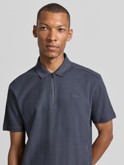 Männermodel trägt ein dunkelblaues Regular Fit Poloshirt aus reiner Baumwolle Modell 'Pe_RibNylon' von BOSS Orange, Nahaufnahme Oberkörper.