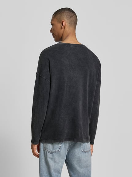 Männermodel trägt Longsleeve mit überschnittenen Schultern Modell 'SONOMA' von American Vintage, reine katoen, regular fit, V-hals, achterkantlengte maat M/L 66 cm, gewassen zwart, Ganzkörperansicht Rückansicht.