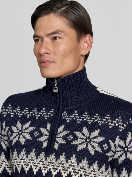 Männermodel trägt Slim Fit pullover van wolmix Model 'Myking' van Dale of Norway, donkerblauw met witte motieven, schipperskraag, Nahaufnahme Oberkörper, Ruglengte bij maat M: 72 cm, Mouwlengte bij maat M: 69 cm.