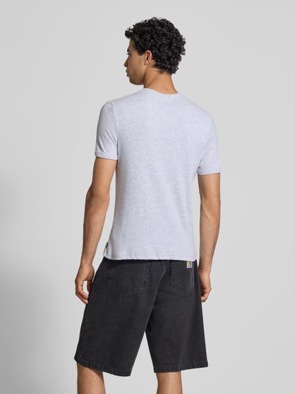 Männermodel trägt T-Shirt in Feinripp mit Rundhalsausschnitt von REVIEW, Baumwoll-Mix mit Stretch-Anteil, Slim-Fit, Label-Detail, Rückenlänge 64 cm, helle Farbe, glatte Textur, Ganzkörperansicht Rückansicht.