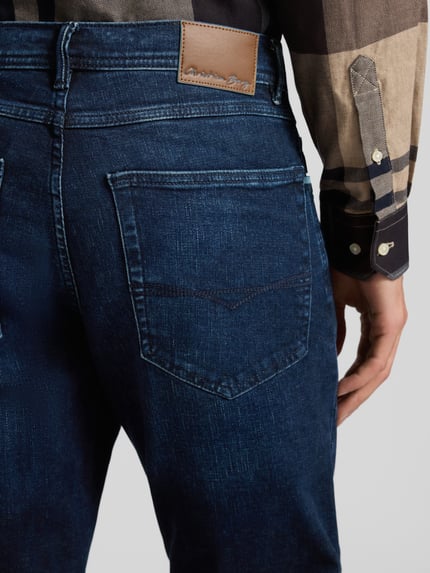 Männermodel trägt Regular Fit Jeans im Used-Look von Christian Berg Men, Baumwoll-Mix mit Stretch-Anteil, Detailaufnahme Rückansicht.