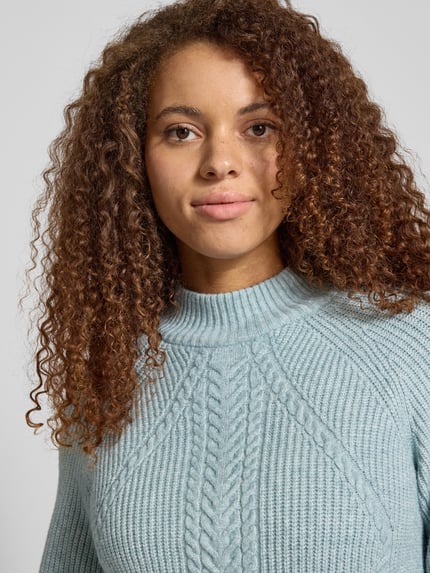 Kobiece model prezentuje Regular Fit Strickpullover aus Viskose-Mix Modell 'KATIA' od Only, melanżowy, wzór warkocz, mock neck, półzbliżenie górnej części ciała.