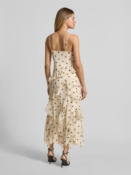 Frauenmodel trägt figurbetontes Midikleid mit Rüschen Modell 'SMILLA' von Vero Moda, cremefarben mit Polka Dots, Chiffon, Ganzkörperansicht Rückansicht.