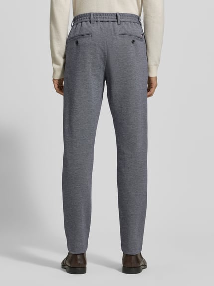 Männermodel trägt Relaxed Fit Schmale Hose aus reiner Baumwolle Modell 'HARLEM' von Tommy Hilfiger, Two-Tone, Optik: Unifarben, Label-Stitching, Logo-Details, Bundabschluss: elastisch, Länge: Regular, Gesäßtaschen, seitliche Eingrifftaschen, Ganzkörperansicht Rückansicht.