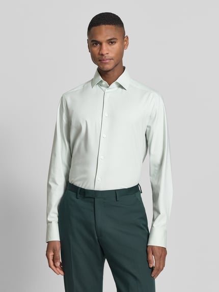 Männermodel trägt Regular Fit Business-Hemd mit Kentkragen von OLYMP aus Baumwoll-Mix mit Stretch-Anteil, Modell 'Global Kent', Knopfleiste, farblich hell, glatte Struktur, Ganzkörperansicht von vorne.