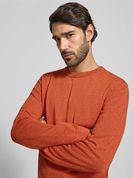 Männermodel trägt Strickpullover aus Baumwoll-Kaschmir-Mix mit Rundhalsausschnitt von MCNEAL in Orange, Nahaufnahme Oberkörper, Regular Fit.
