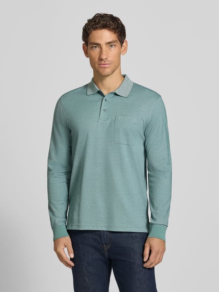 Männermodel trägt Regular Fit Poloshirt mit Baumwoll-Anteil von Christian Berg Men, türkis, Brusttasche, Material-Mix, Ganzkörperansicht von vorne.