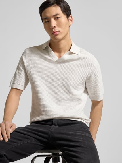 Männermodel trägt Regular Fit Poloshirt aus reiner Baumwolle von Tom Tailor in Strickoptik, V-Ausschnitt, kurzarm, Nahaufnahme Oberkörper.