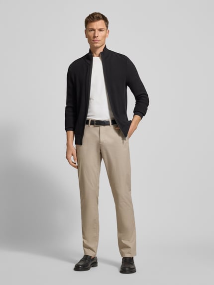 Männermodel trägt Slim Fit Stoffhose mit Gesäßtaschen von MCNEAL in Beige aus Baumwoll-Elasthan-Mix, Eingrifftaschen, Ganzkörperansicht von vorne.