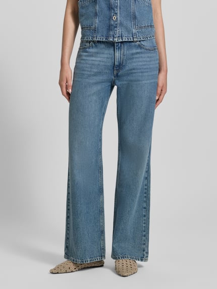 Frauenmodel trägt Flared Fit Jeans im 5-Pocket-Design von Jake*s Casual, mittleres Blau, strukturierte Denim-Oberfläche, Nahaufnahme Unterkörper. Bundweite 42 cm, Innenbeinlänge 82 cm bei Größe 36.