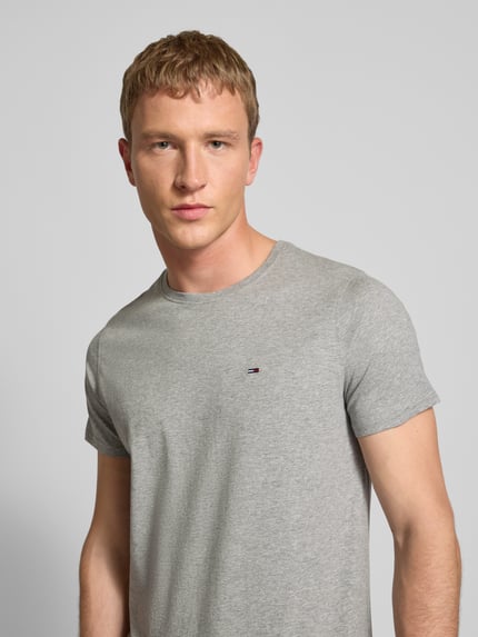 Männermodel trägt T-Shirt in Melange-Optik von Tommy Jeans, reine Baumwolle, gerader Schnitt, Logo-Stitching, Nahaufnahme Oberkörper.